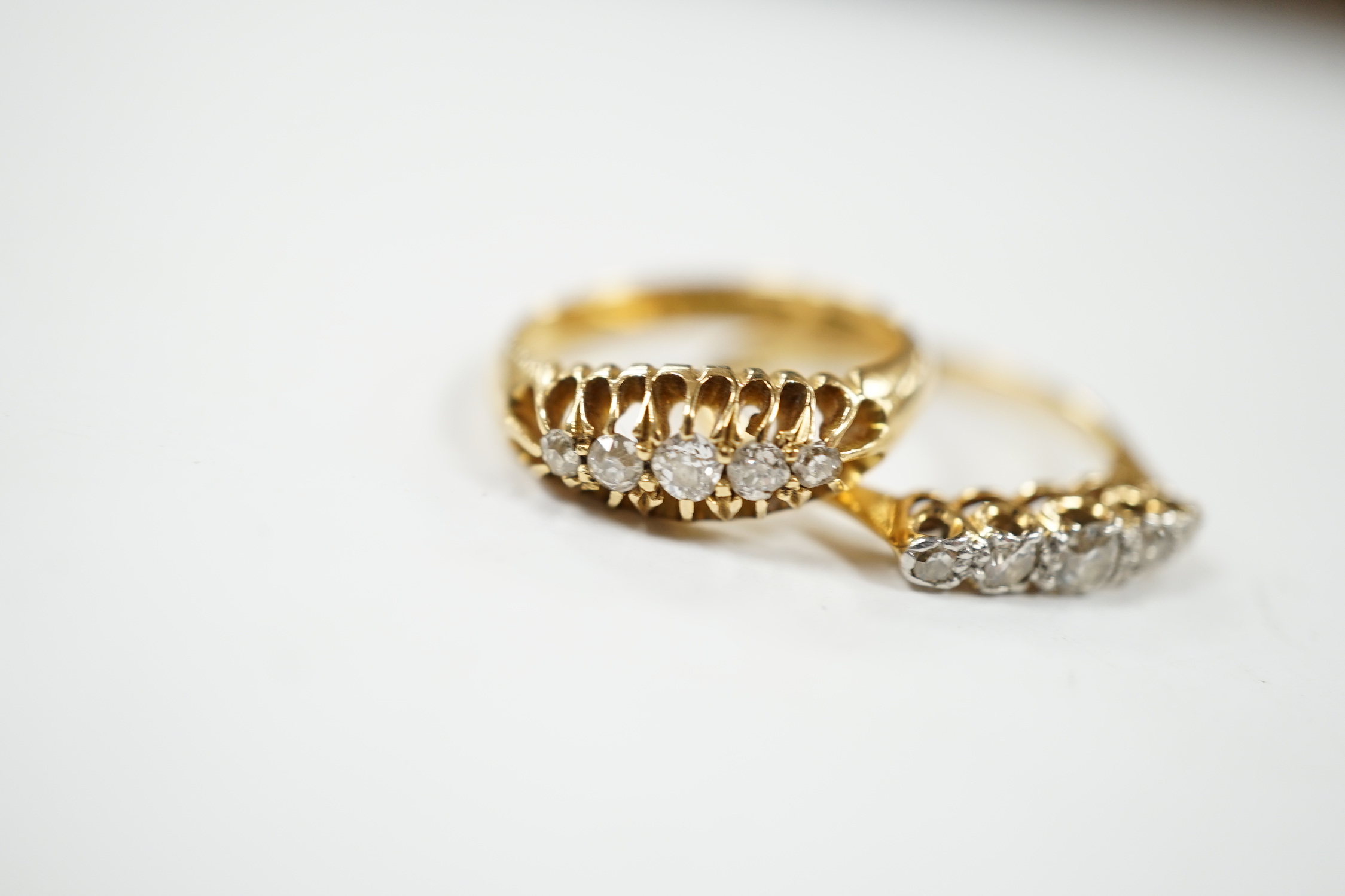 Two early 20th century 18ct gold and graduated five stone diamond set half hoop rings